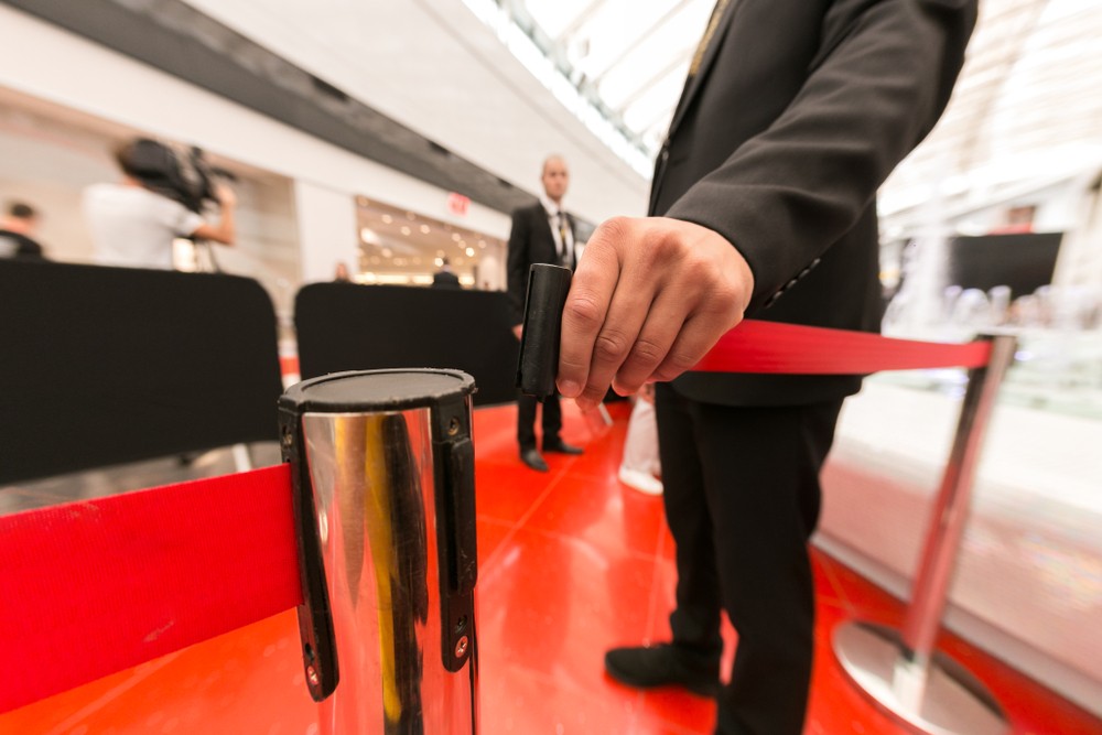 Empfangsdienst und Doorman: Mitarbeiter öffnet die Absperrung am Eingang