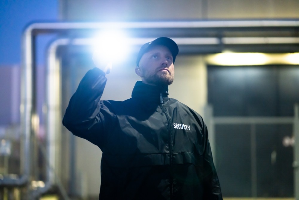 Werkschutz: Sicherheitsmitarbeiter kontrolliert nachts ein Industriegelände